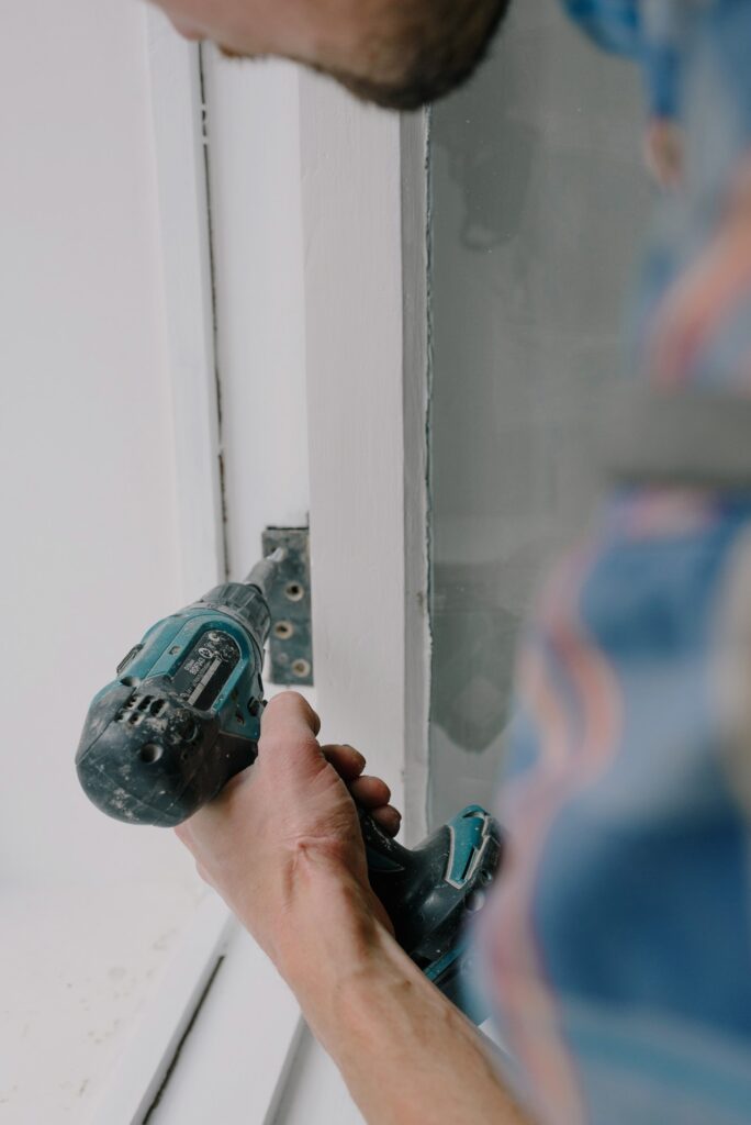 Hombre usando el atornillador en una ventana de madera