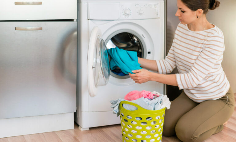 mujer recogiendo la ropa de un lavarropas